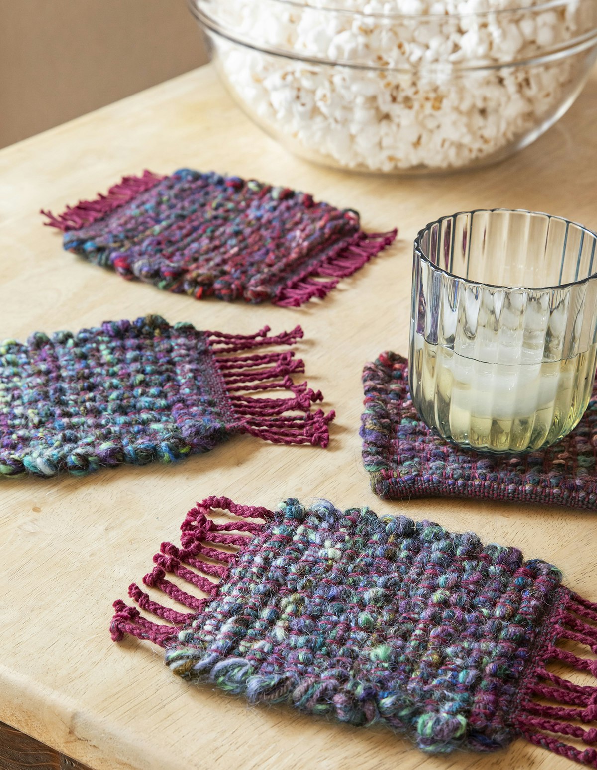 Four coasters woven in shades of blue with deep red.