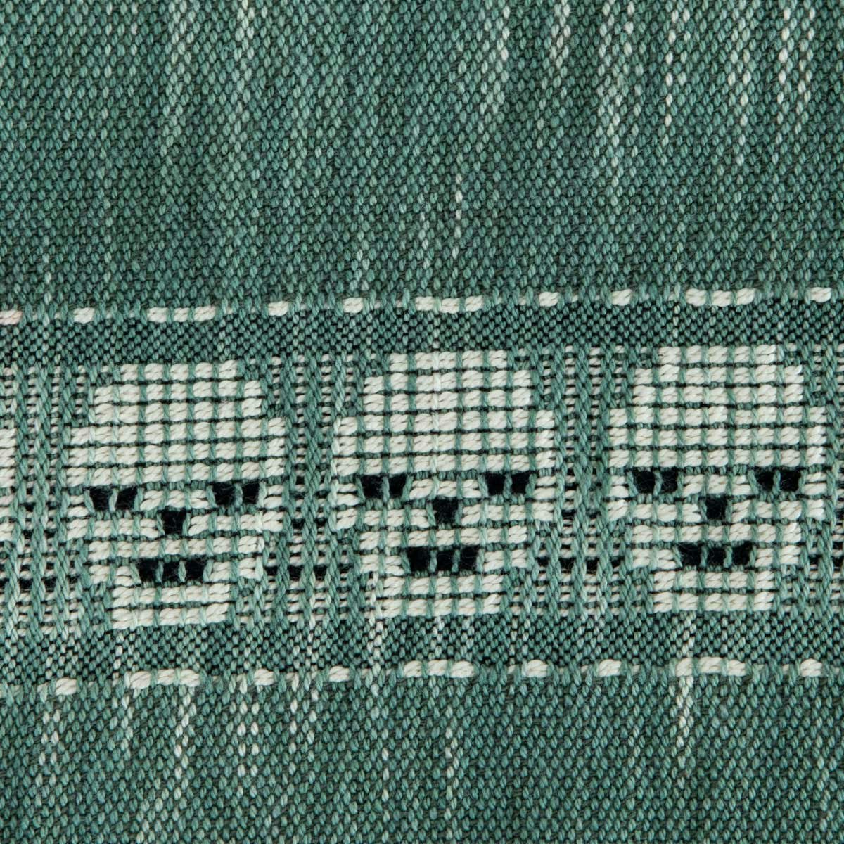 A variegated green textile with a series of white skulls.