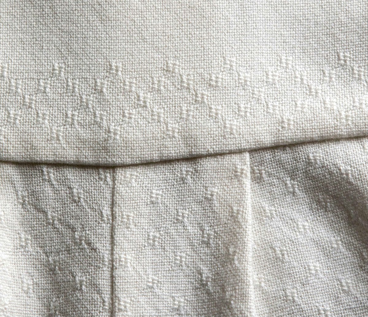 A white textile with raised patterning.