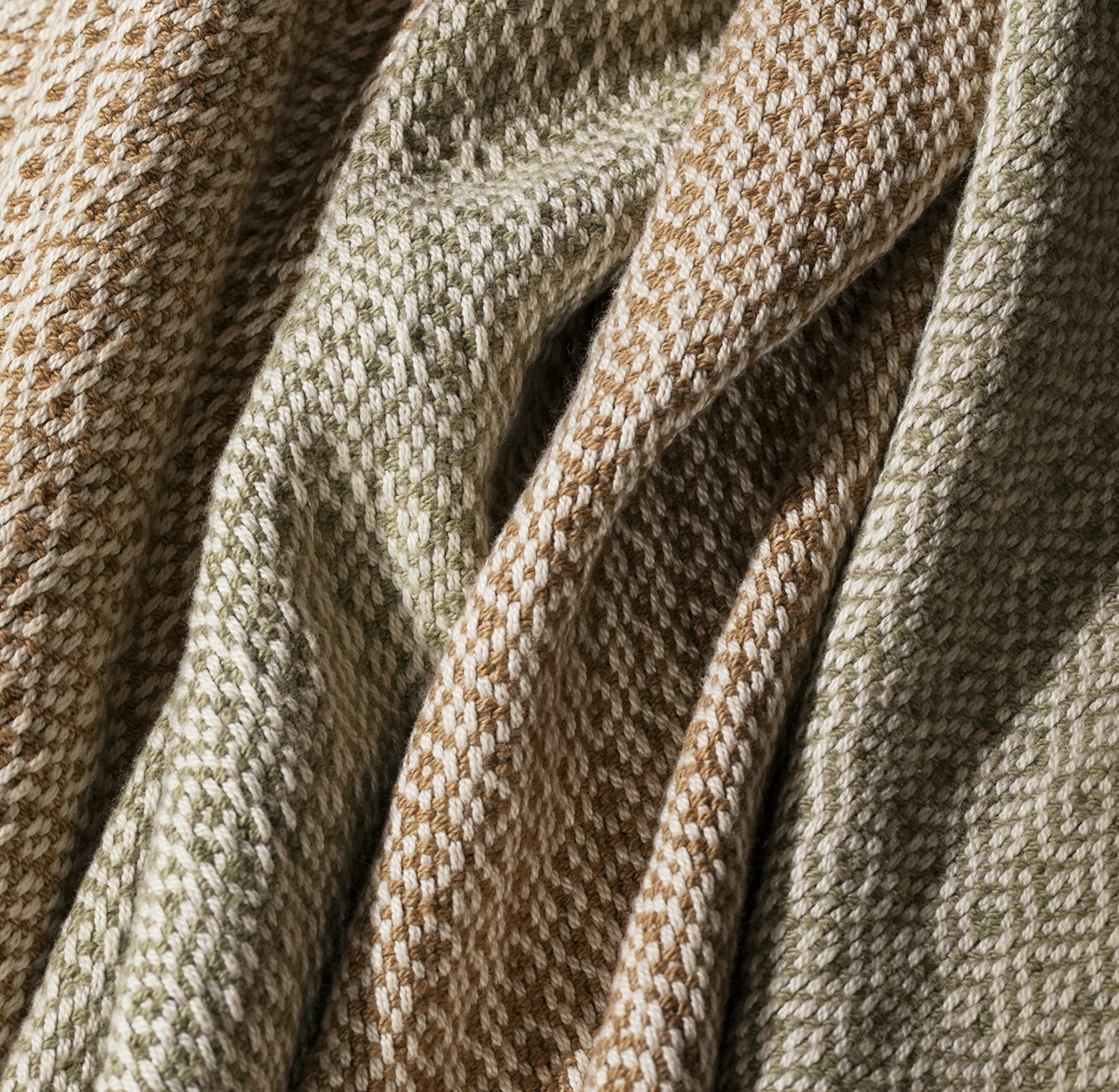 A close-up look at four towels in cream, green, and brown.