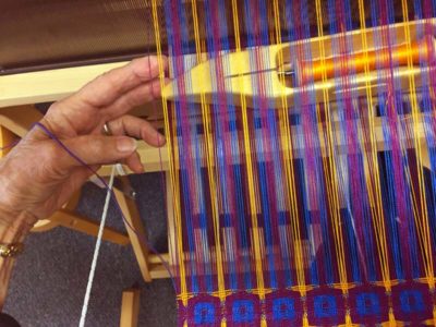 Bring the shuttle out of the next shed under the floating selvedge and under the inactive wefts.